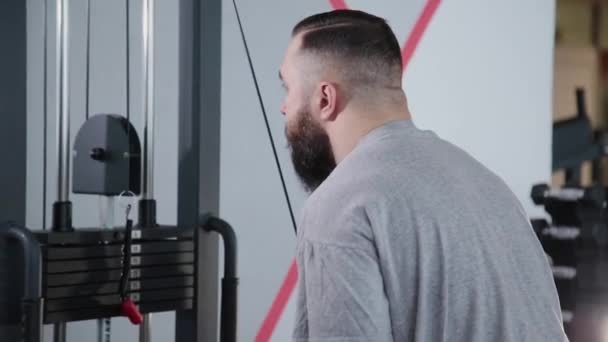 Handsome athletic man trains triceps on the block simulator in the gym. - Footage, Video