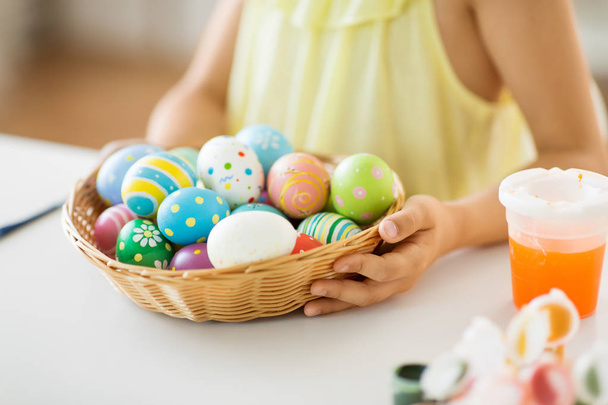 close up of girl with easter eggs in wicker basket - Foto, Imagem