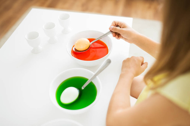 girl coloring easter eggs by liquid dye at home - Foto, afbeelding