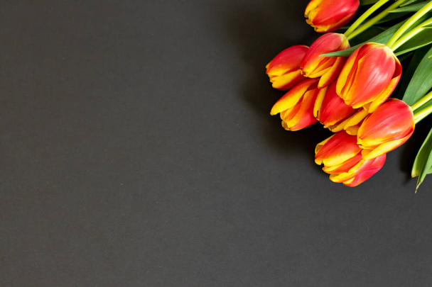 rote Tulpen auf schwarzem Hintergrund. flache Lage, Draufsicht. Hintergrund zum Frauentag - Foto, Bild
