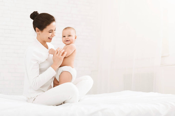 junge Mutter sitzt mit Baby im Bett - Foto, Bild