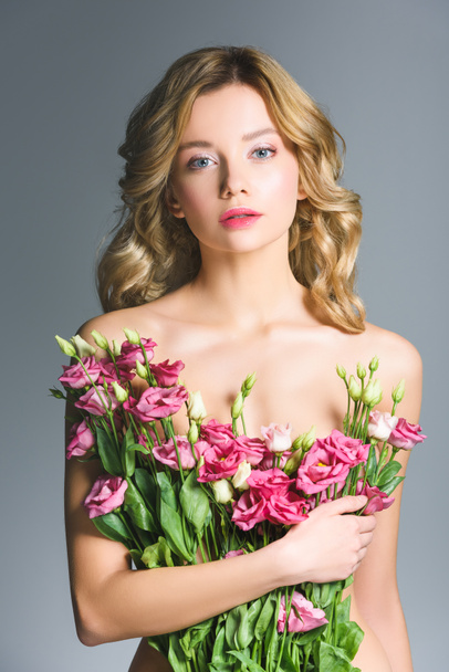 naked girl holding bouquet of eustoma flowers isolated on grey - Zdjęcie, obraz