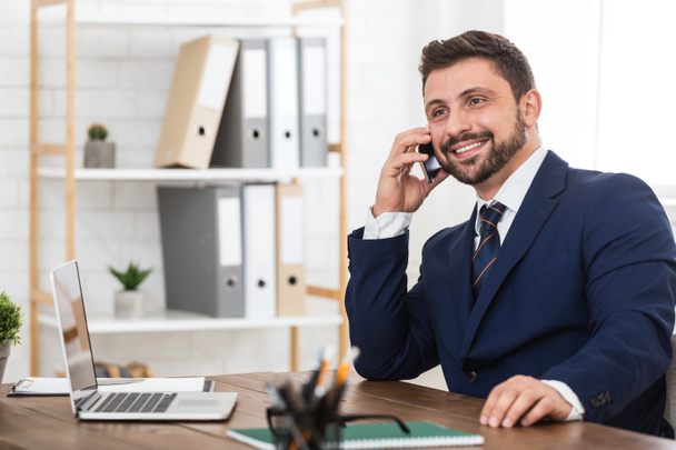 Liikemies puhuu puhelimessa kumppaneiden kanssa ja hymyilee
 - Valokuva, kuva