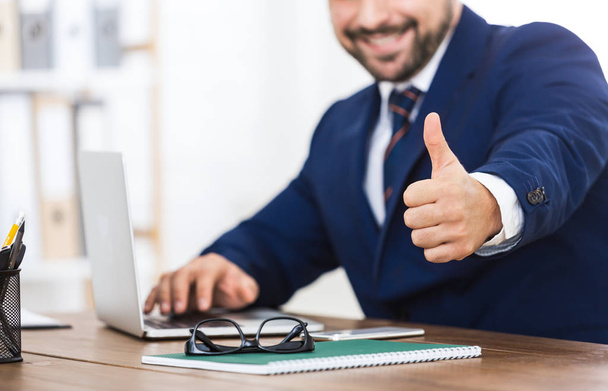 Успешный бизнесмен показывает большой палец на рабочем месте
 - Фото, изображение