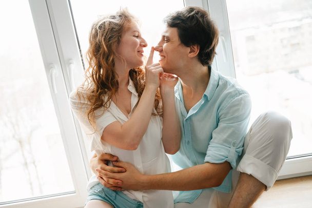 Happy girl and man kissing near window in home.  - Foto, imagen
