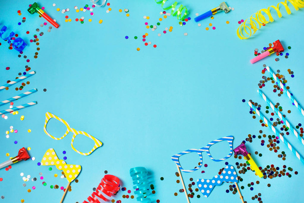 Urlaub oder Party Rahmen Hintergrund mit Strohhalmen, Trillerpfeifen, Konfetti, lustige Gläser und Luftschlange auf blauem Hintergrund. flache Verlegestile. - Foto, Bild