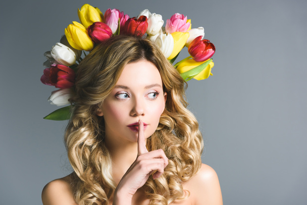 girl with wreath of flowers on hair showing hush sign isolated on grey - Фото, зображення