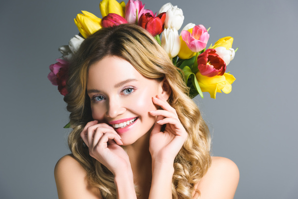 smiling woman with wreath of flowers on hair isolated on grey - Foto, afbeelding