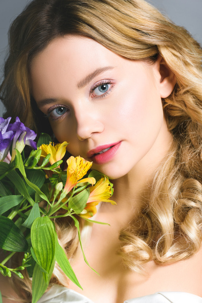 attractive blonde young woman with flowers looking at camera - Foto, imagen