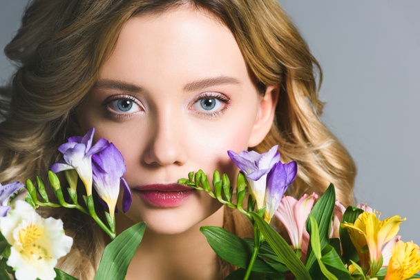 beautiful blonde young woman with flowers looking at camera - Foto, afbeelding