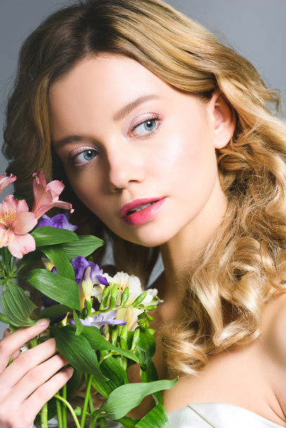 surprised blonde young woman holding flowers in hand - Фото, зображення