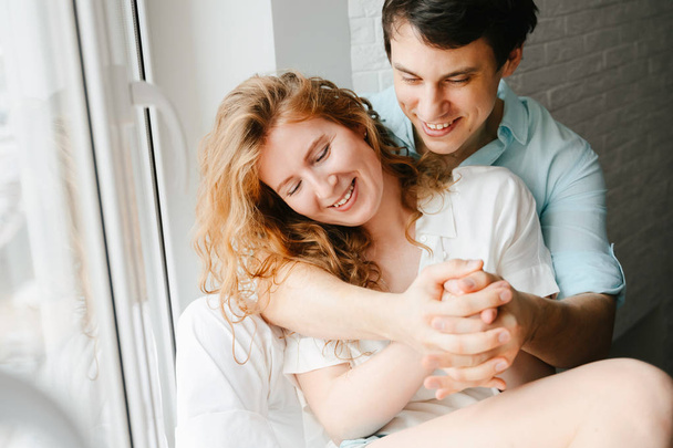 Happy girl and man hugging near window in home.  - Foto, Imagem
