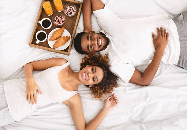 Boldog fekete pár élvezi a reggelit az ágyban - Fotó, kép