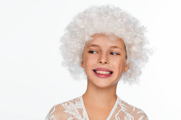 Portrait of a cheerful, energetic eight-year-old girl in a white wig and with white freckles. White background - Фото, зображення