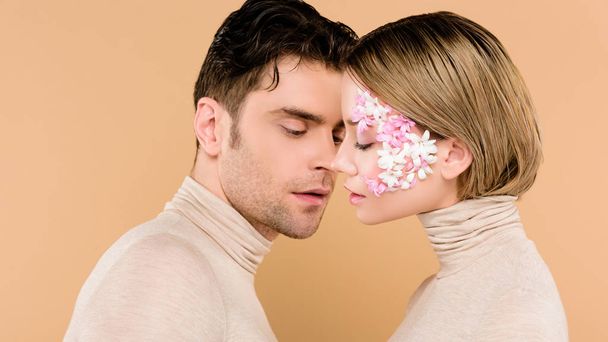 handsome man looking at pretty girlfriend with closed eyes isolated on beige  - Photo, Image