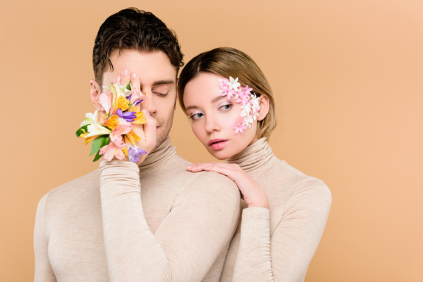 mies alstroemeria kukkia kädessä kattaa toisen silmän lähellä kaunis nainen kukkia kasvot eristetty beige
  - Valokuva, kuva