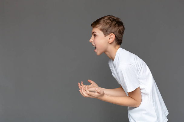 Zdenerwowany chłopak krzyczy i gestykulacji rękami w powietrzu - Zdjęcie, obraz
