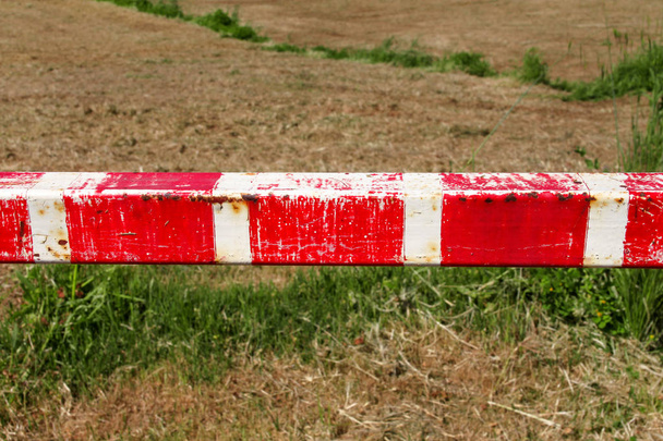 警告のサイン、自然の中で緑の芝生に赤と白の標識バリアの詳細をクローズ アップ。輸送および交通規制。古いフェンス作られた、白と赤の路上パーキングの壁ランプおよびコントロール ポイント. - 写真・画像