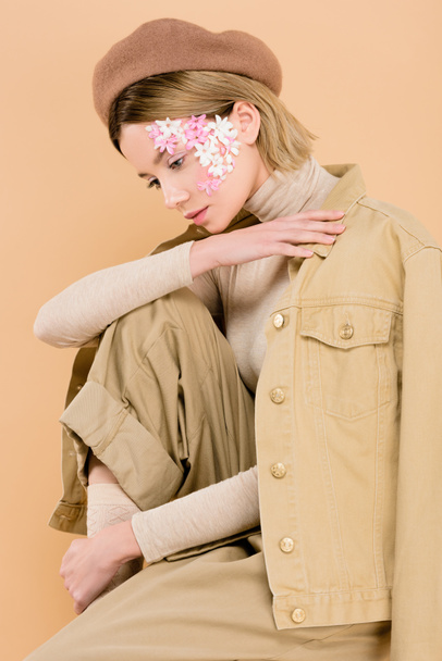 trendy woman with flowers on face wearing beret isolated on beige  - Foto, afbeelding