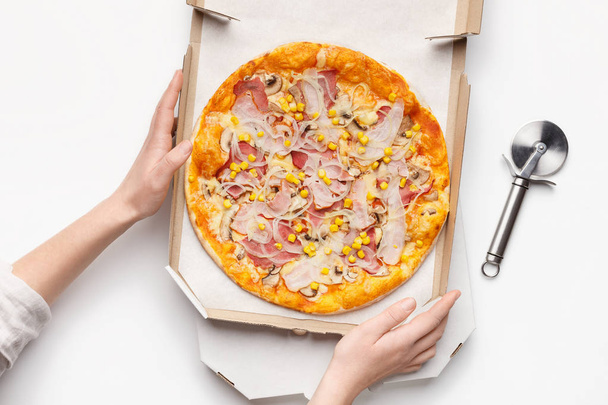 Woman holding cardboard box with pizza, top view - Fotoğraf, Görsel