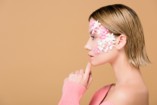 side view of attractive woman with flowers on face isolated on beige - Foto, imagen