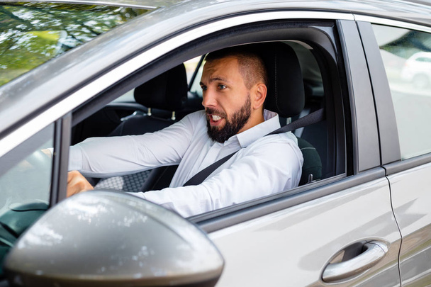 Side view of frustrated young bearded man driving a car. - Foto, immagini