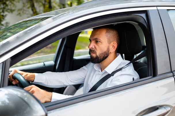 Side view of frustrated young bearded man driving a car. - Photo, image