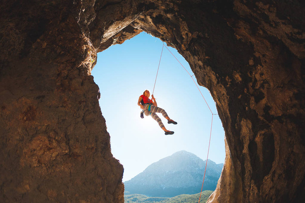 Bergsteiger steigt in die Höhle. Felsen in Form eines Bogens. Die Frau trainiert auf natürlichem Terrain. das Mädchen überwindet die schwierige Kletterroute auf den türkischen Felsen. - Foto, Bild