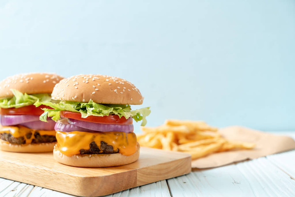 fresh tasty beef burger with cheese and french fries on wood background - Foto, imagen