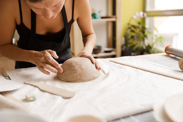 Крупним планом жінка, що виготовляє керамічний та керамічний посуд на майстерні, працює з глиною
 - Фото, зображення
