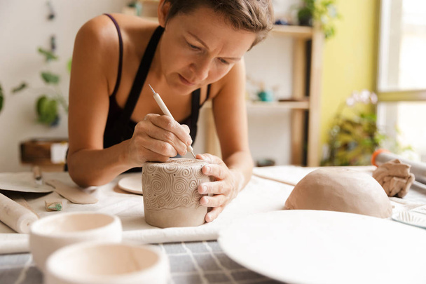 Young woman ceramic and pottery tableware at the workshop - Фото, изображение