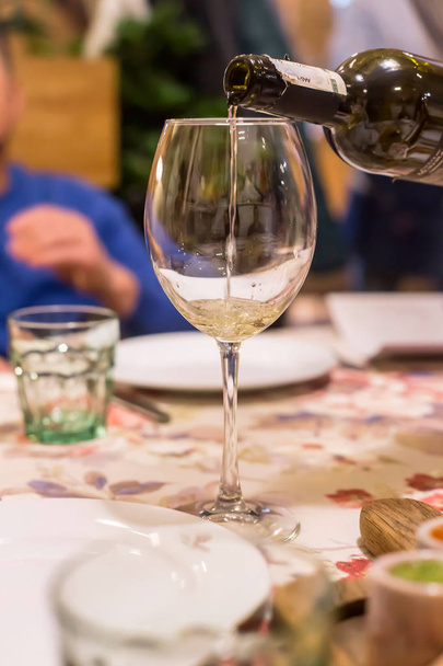 Сомельє вливає вино в келих гостей ресторану за вечерею
 - Фото, зображення