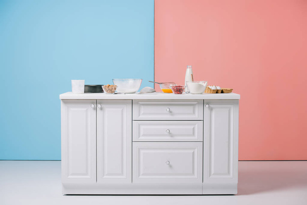 tavolo da cucina bianco con vari utensili da cucina e prodotti su sfondo bicolore
 - Foto, immagini