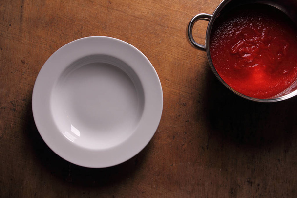 Placa vacía sobre mesa de madera con sopa de tomate fresca
 - Foto, imagen