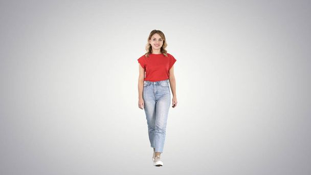 Casual woman walking and smiling on gradient background. - Photo, image