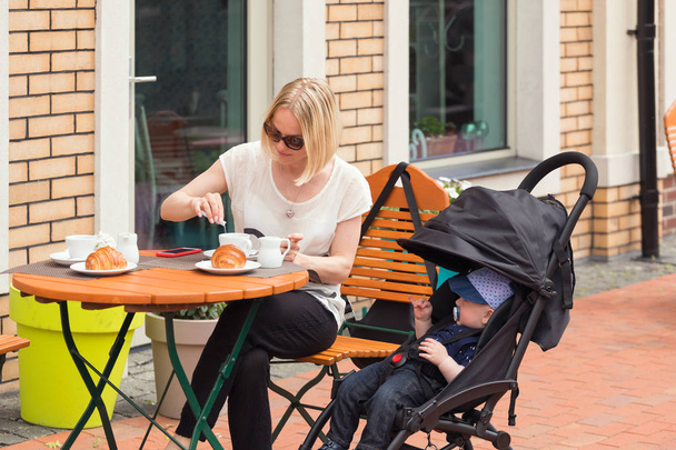 Young mother with her one-year-old child in a street cafe - Photo, Image