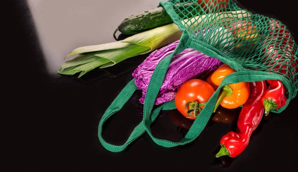 verduras frescas, productos de jardín, comer limpio y el concepto de dieta. Vegetal en una bolsa de algodón neta sobre fondo negro
 - Foto, Imagen