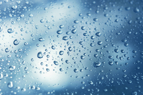 El agua real cae sobre fondo de gradación azul, se cierra. Las precipitaciones en el cristal de la ventana. Condenación - Foto, imagen