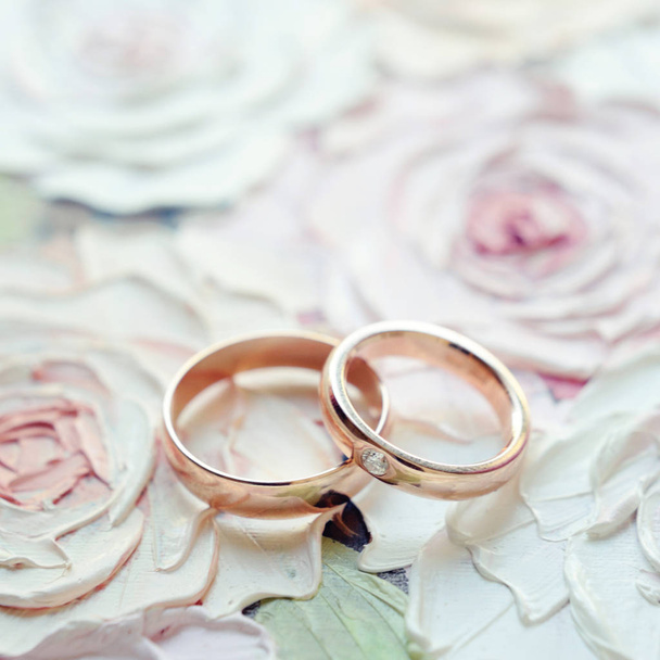 Anneaux de mariage dorés classiques sur le fond de roses peintes florales. Carte d'invitation
 - Photo, image