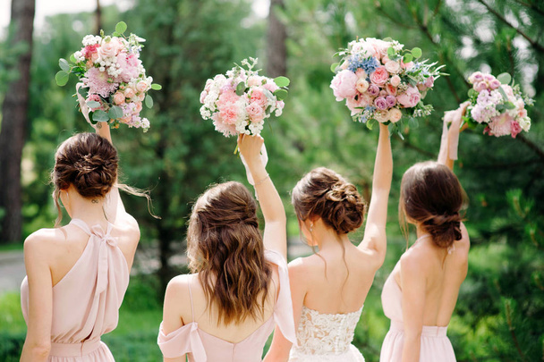 Družičky v růžových šatech držící svatební kytice venku. Šťastný svatební koncept.  - Fotografie, Obrázek