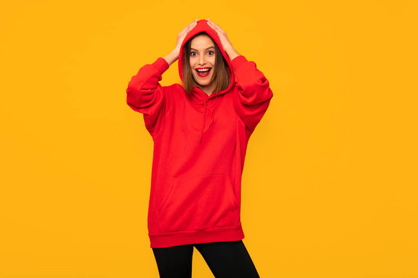 cool young woman posing with a red hoodie, hipster woman on yellow background - Photo, image