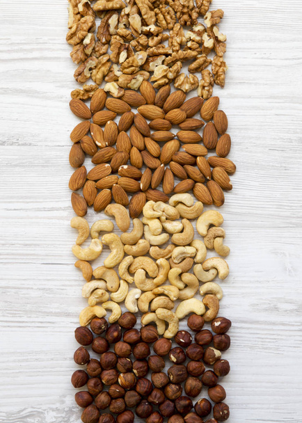 Various nuts on white wooden table. Cashew, hazelnuts, walnuts, almonds. Top view, flat lay. Closeup. - Φωτογραφία, εικόνα
