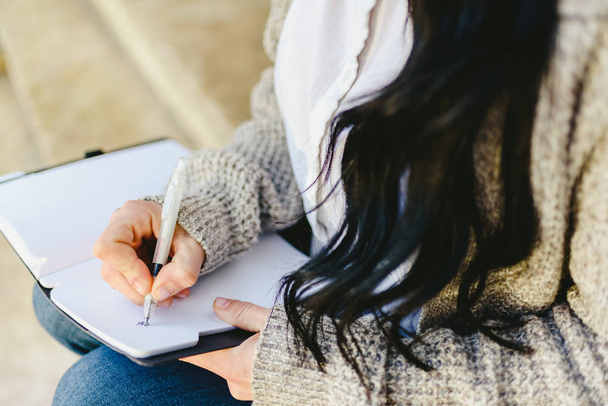 Mano de mujer tomando notas en su cuaderno con pluma, sentada
. - Foto, imagen