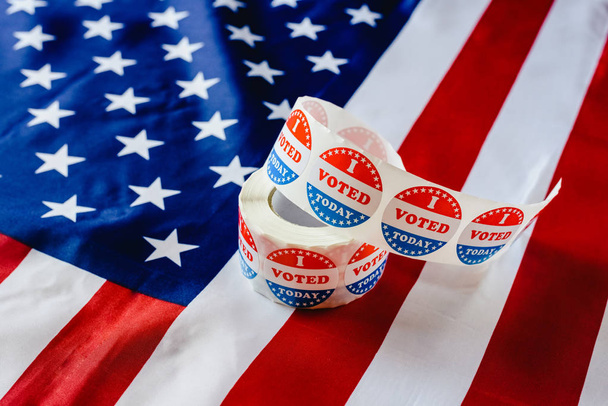 I vote today stickers roll, in US elections on American flag. - Photo, Image