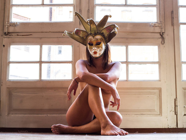 Smyslná mladá nahá žena v benátské masky pózuje v retro interiér  - Fotografie, Obrázek