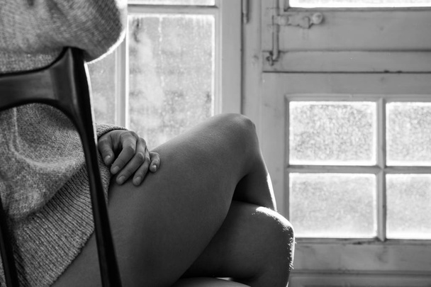 裸の脚の椅子に座ってセーターの女性の表示を閉じる - 写真・画像