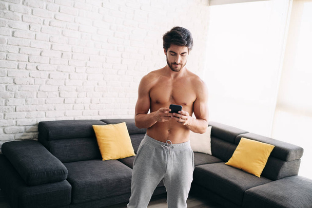 Hombre haciendo ejercicio en casa con aplicación en el teléfono móvil
 - Foto, imagen