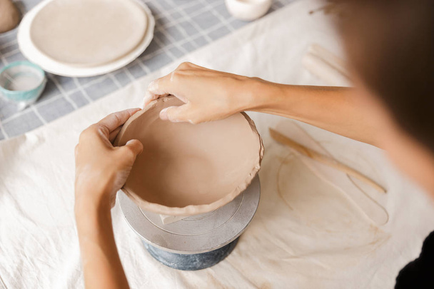Close up of a woman making ceramic and pottery tableware at the workshop, working with clay - 写真・画像