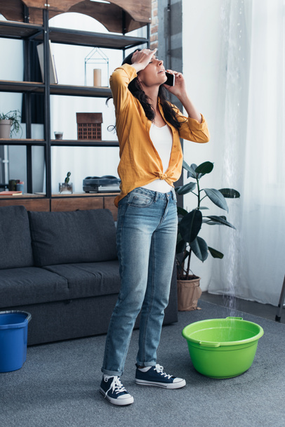 Tired woman in jeans talking on phone in living room - Foto, afbeelding