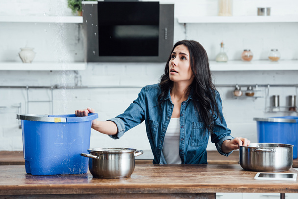 Confused brunette woman dealing with water damage in kitchen - Fotografie, Obrázek